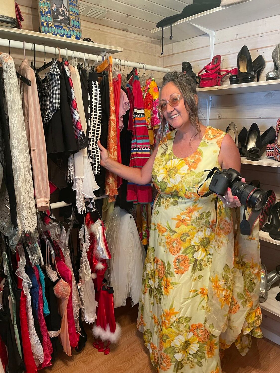 Wolfrum in the wardrobe building of Goddess Studio with her camera explaining the many clothing options women can choose to be photographed in to bring out their inner goddess.